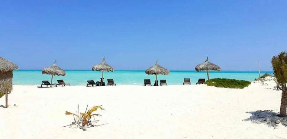 Plage de sable blanc et paillotes face au lagon d'Ambatomilo