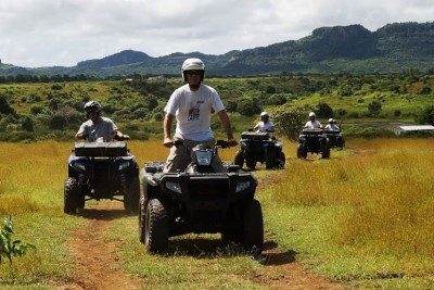 Groupe en quad sur une piste herbeuse, collines en arrière-plan